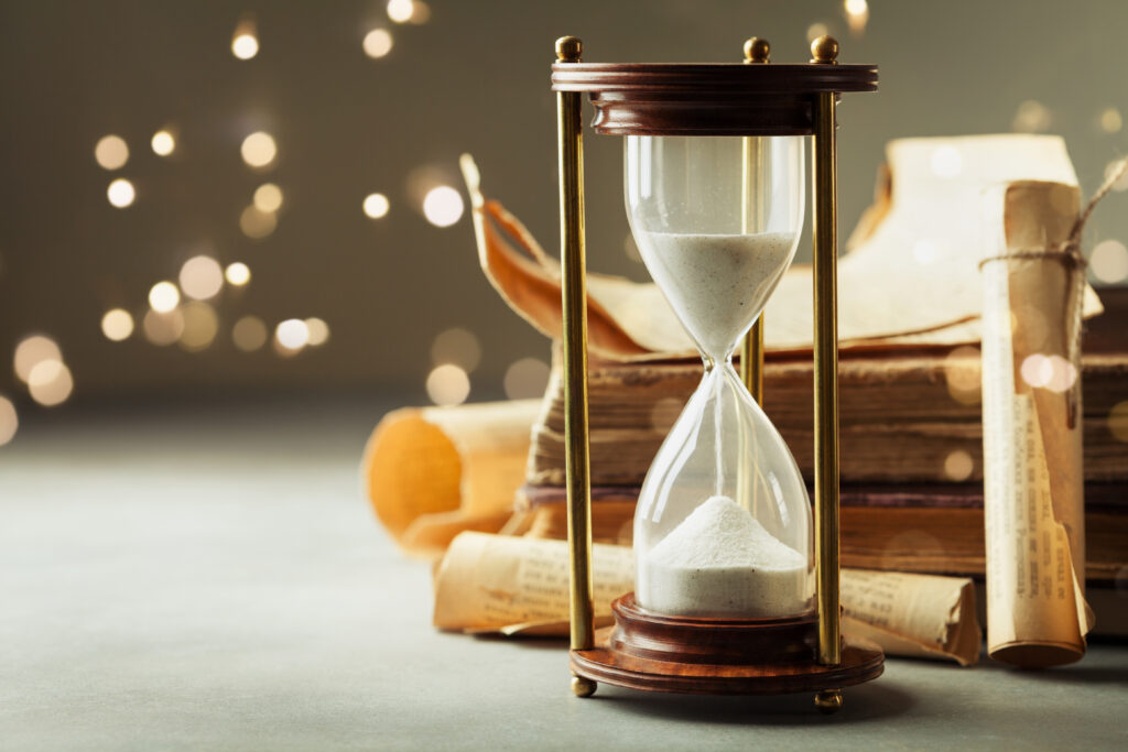 Sand running through the hourglass and old vintage books.
